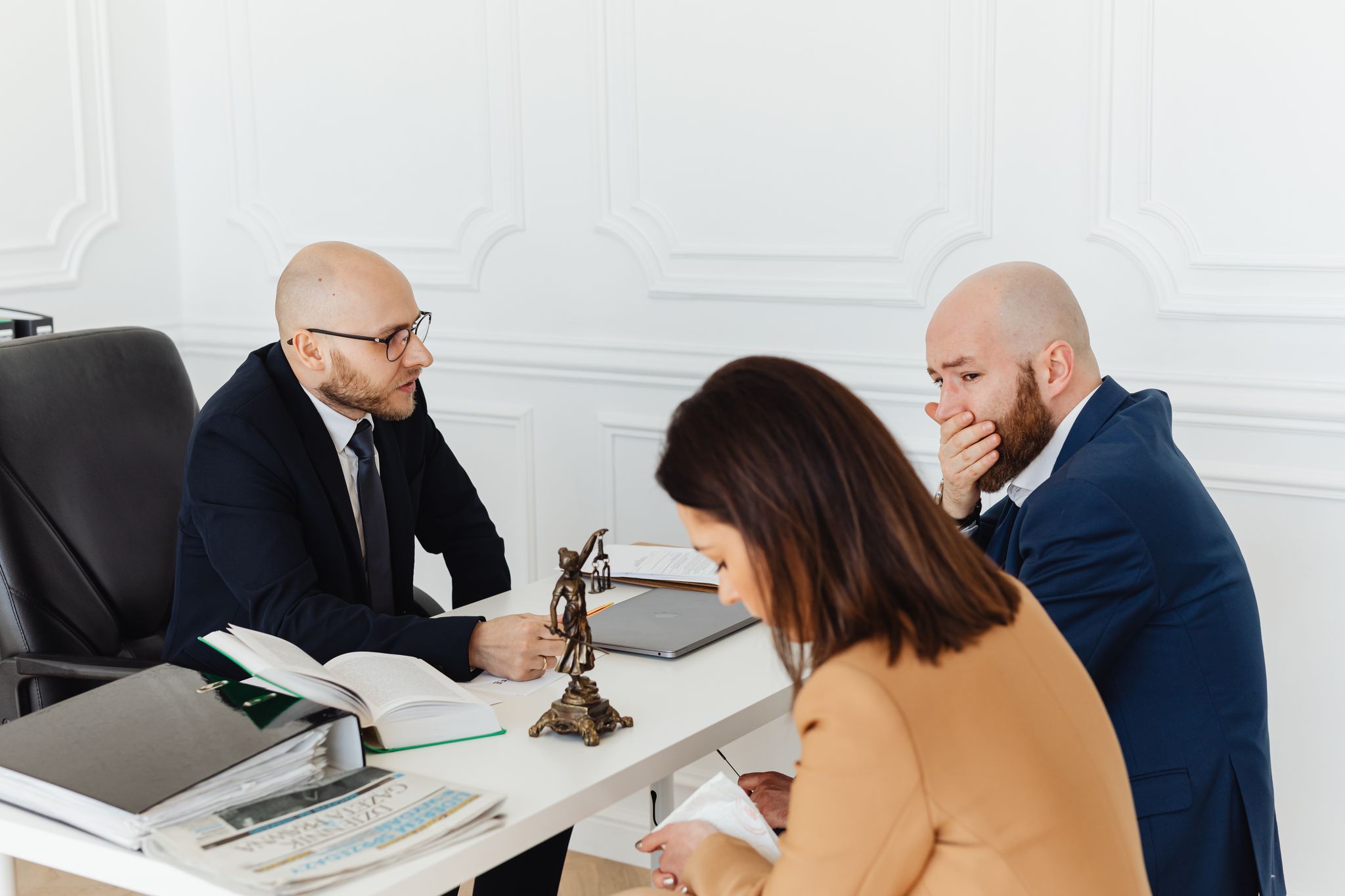 A serious legal consultation in a professional office environment involving three adults.